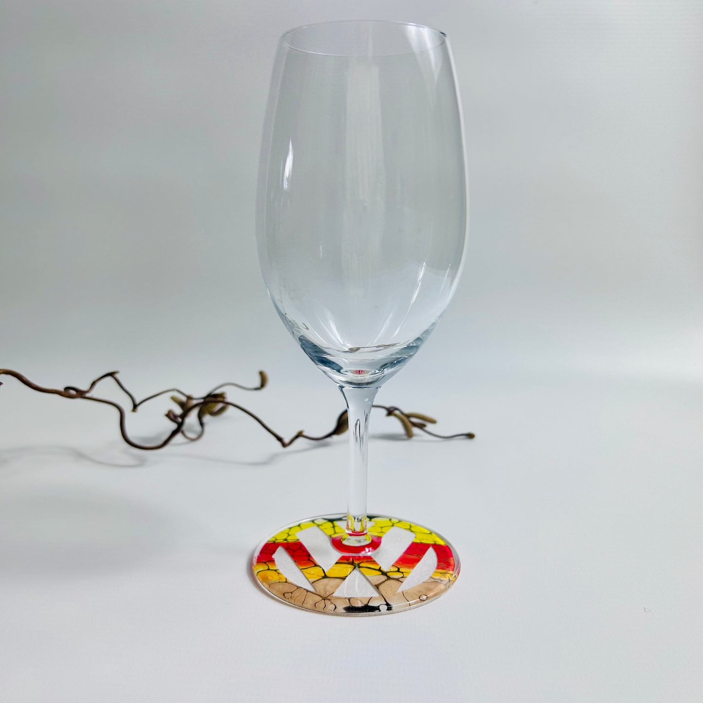 Prosecco glass with yellow and red fluid art design logo on the base, sealed with resin