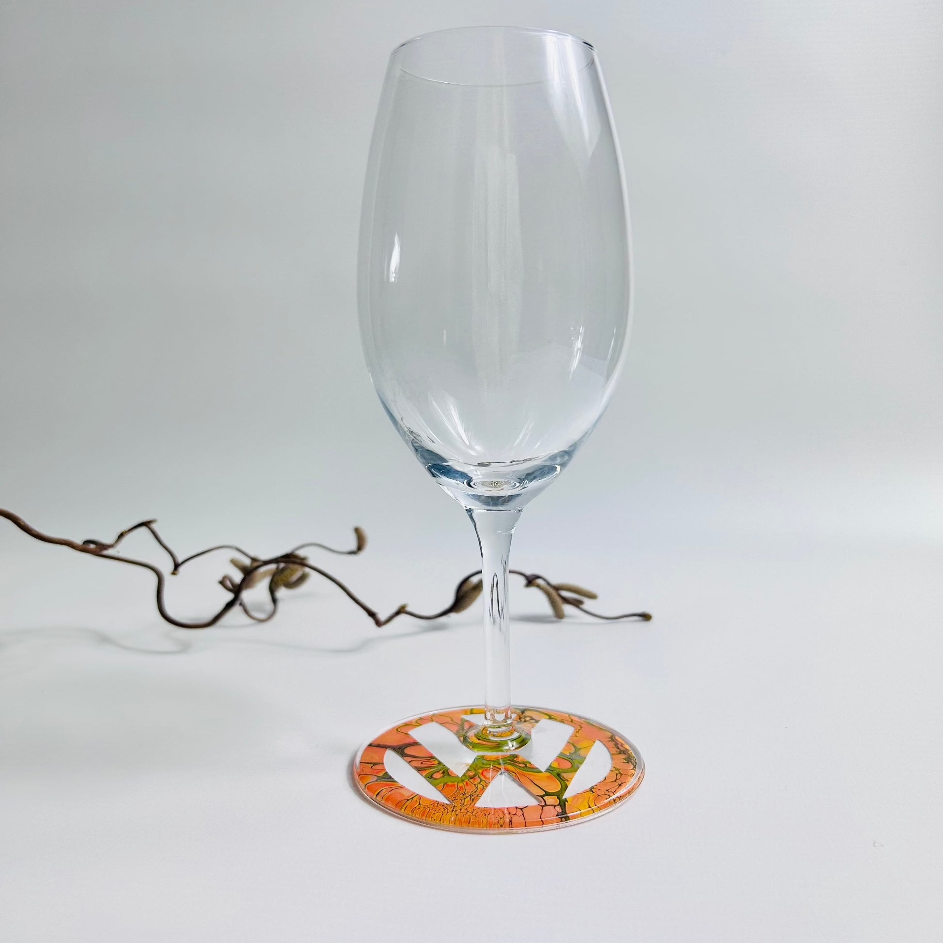 Prosecco glass with orange fluid art logo on the base, sealed with resin