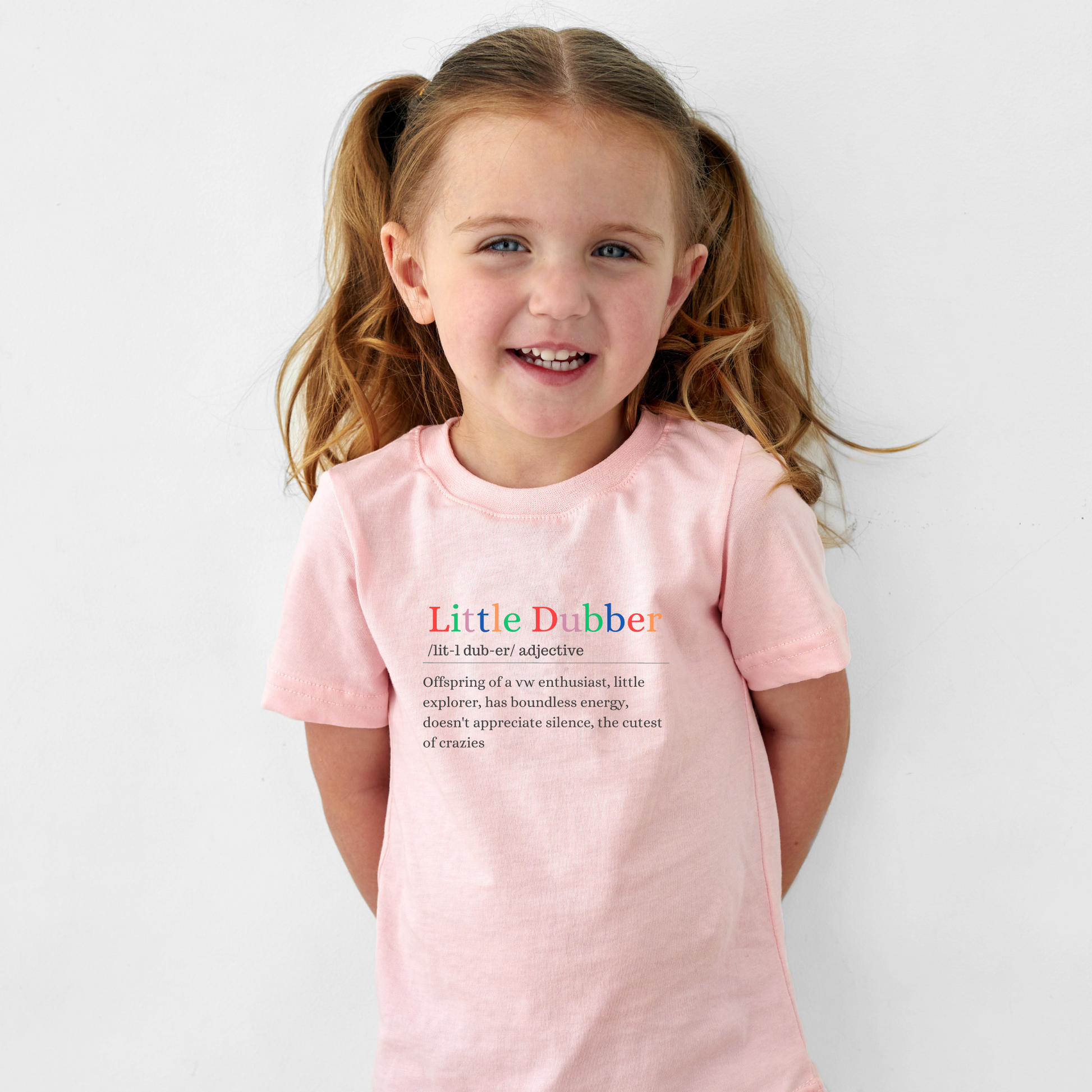 Pink t shirt which has a print in colour stating a Little dubber definition, Offspring of a VW enthusiast, little explorer, has boundles energy, doesn't appreciate silence, the cutest of crazies
